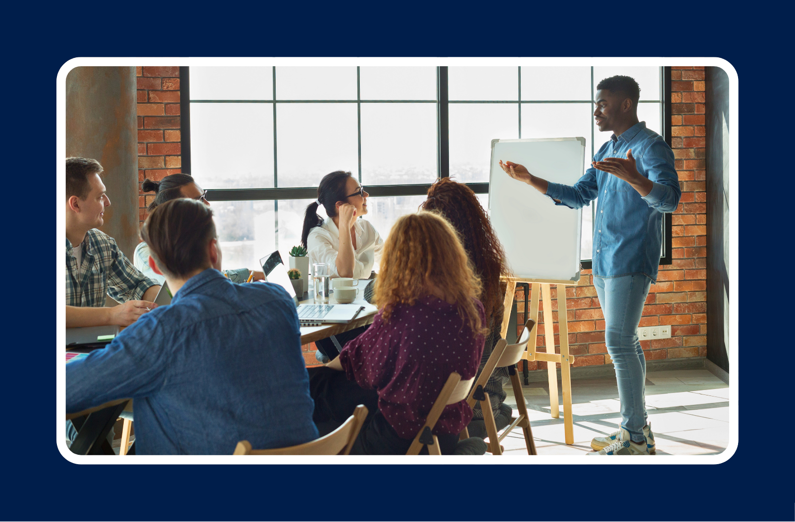 young person giving presentation to coworkers. presenter is standing up while the team is sitting down.
