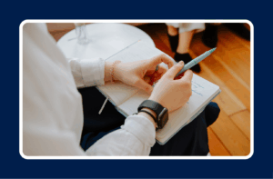 A person holding a pen and notebook, reviewing handwritten notes, symbolizing the process of how to evaluate job advice and reflect on career decisions.