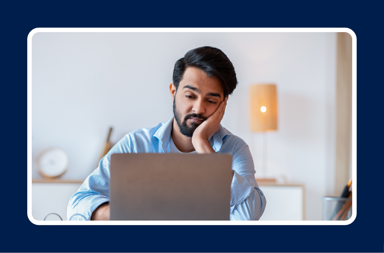 Employee sitting at a desk looking disengaged and unmotivated, reflecting low workplace morale in a remote work environment