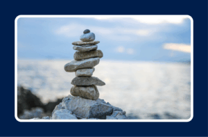 Stacked stones balanced by the ocean, symbolizing contract work stability and career balance.