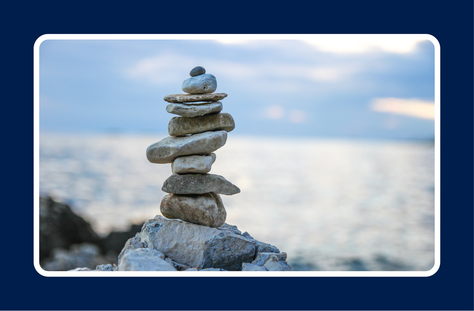 Stacked stones balanced by the ocean, symbolizing contract work stability and career balance.