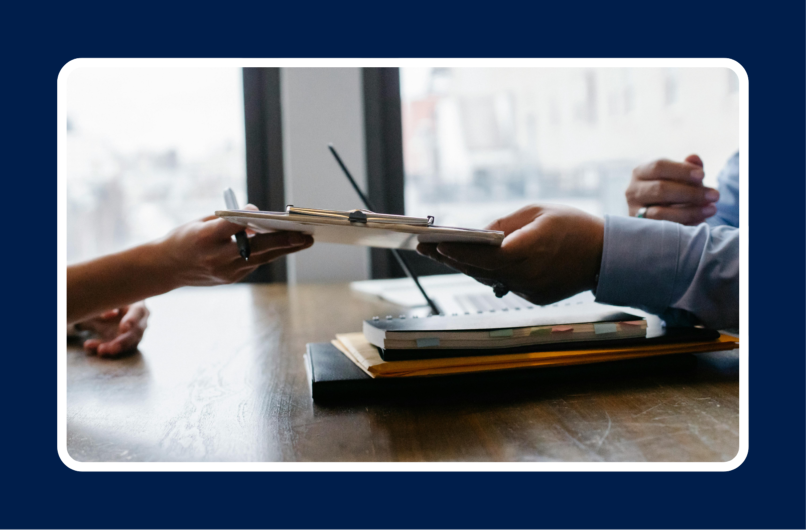 Two professionals exchanging a clipboard during an interview, representing IT hiring managers building an Ideal Candidate Profile IT to streamline recruitment.