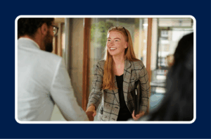Young professional smiling and shaking hands on her first day at work, symbolizing confidence and how to succeed in your first job.