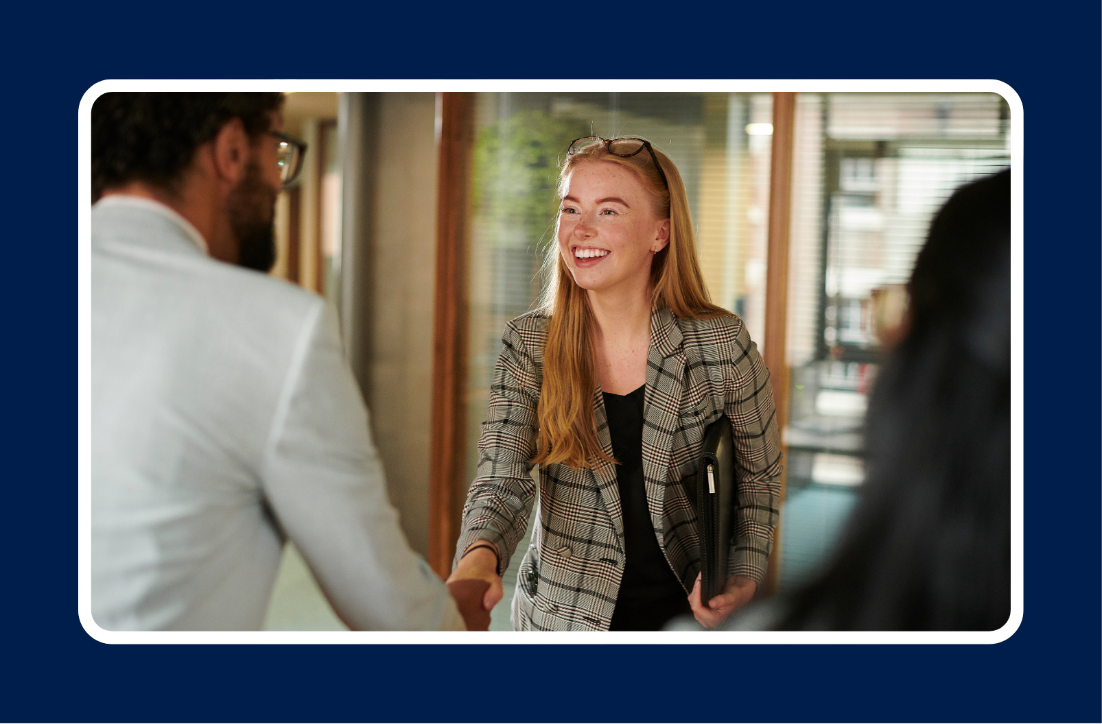 Young professional smiling and shaking hands on her first day at work, symbolizing confidence and how to succeed in your first job.