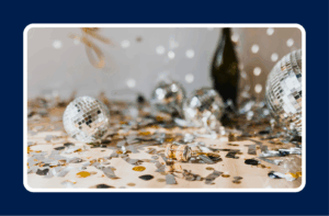 Confetti, disco balls, and champagne corks scattered on a table after a company holiday party celebration, capturing a festive workplace event atmosphere.
