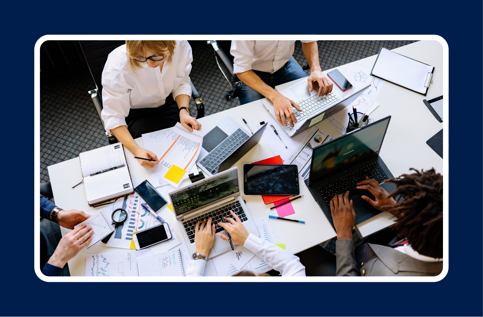 tech team collaborating around a table with laptops, representing imposter syndrome in tech teams and the importance of psychological safety