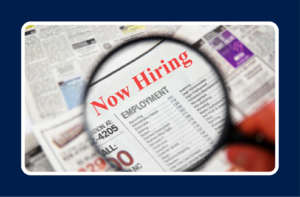 Now hiring job listings viewed through a magnifying glass, representing improving your hiring process