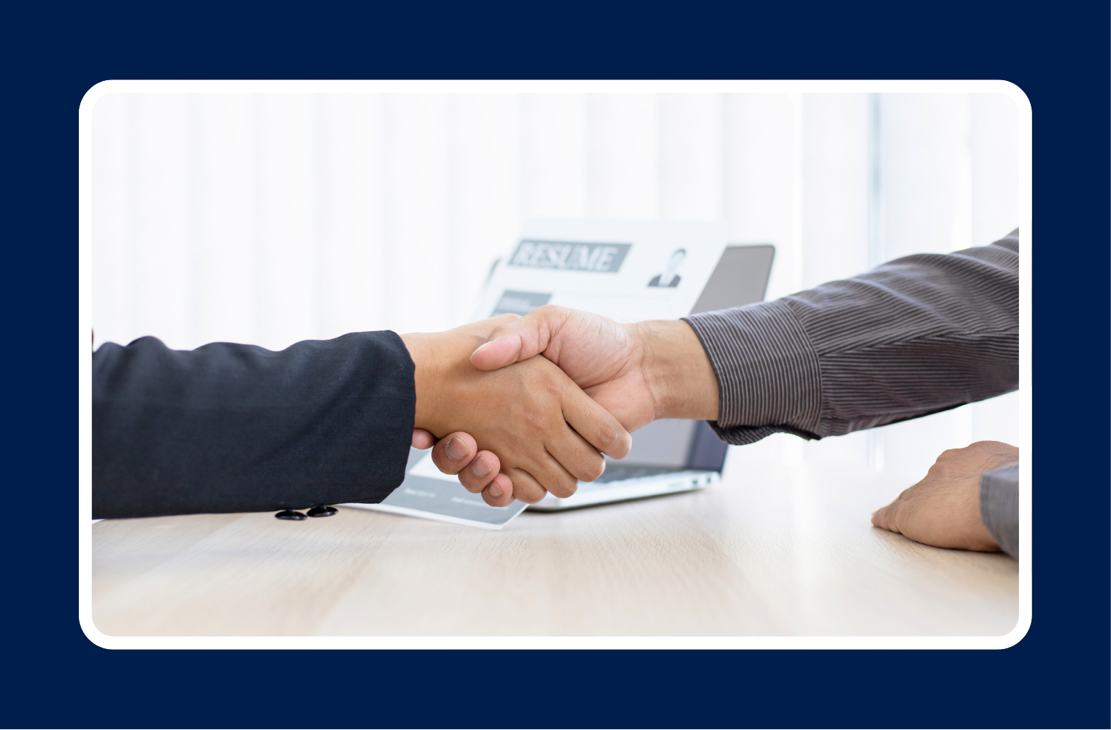 Two business professionals shaking hands across a desk, representing a hiring decision and the importance of understanding the cost of a misaligned hire.