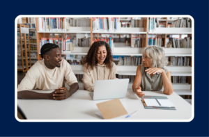 Three professionals collaborating around a laptop in a library, highlighting professional development and how to choose what skills to learn for career growth.